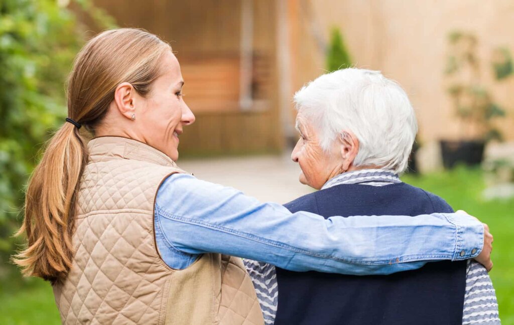 Senior memory care resident walking outdoors with her caregiver at Quincy Place Senior Living in Holland, MI