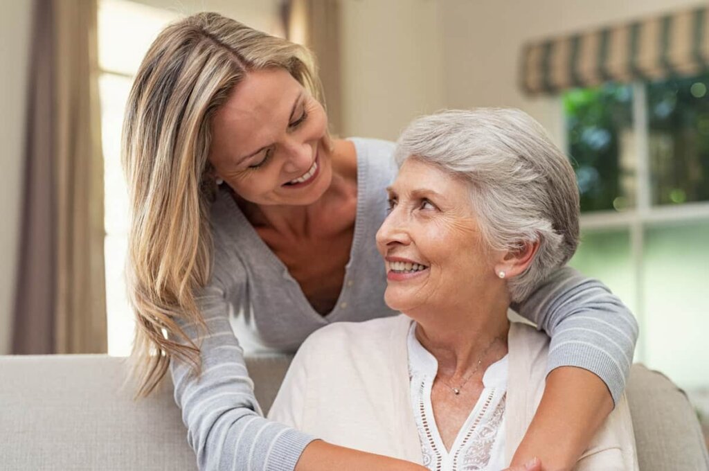 Female resident at Quincy Place Senior Living sitting on a couch in her apartment with her daughter