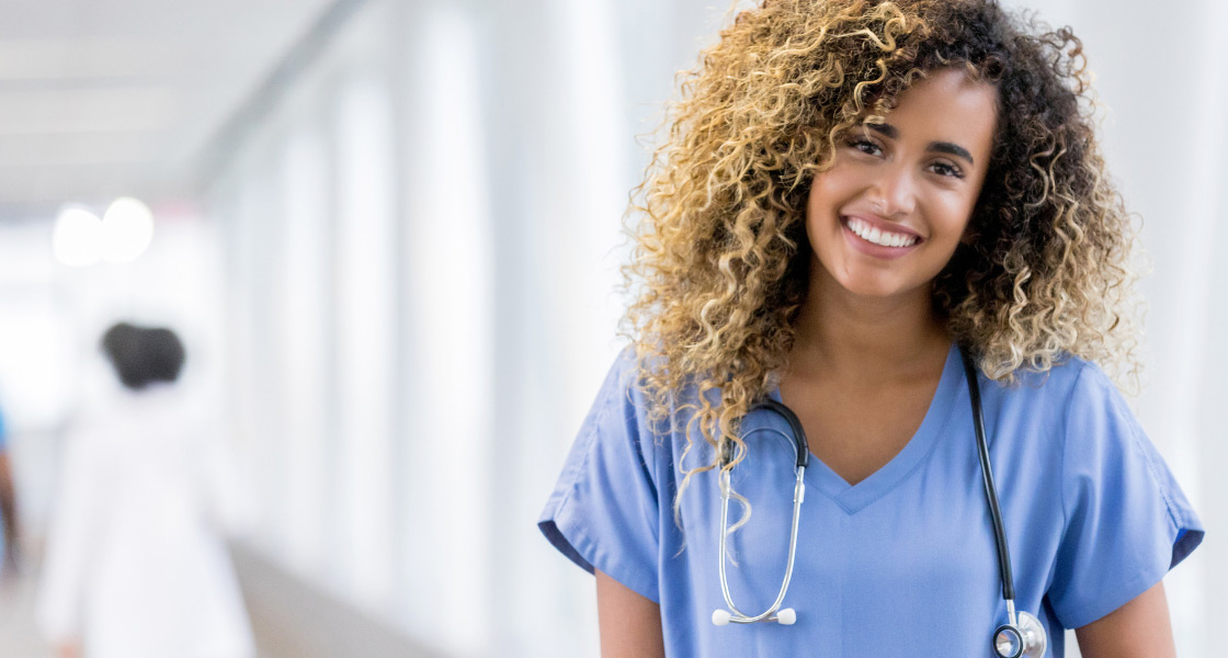 A caregiver with curly hair wearing scrubs and