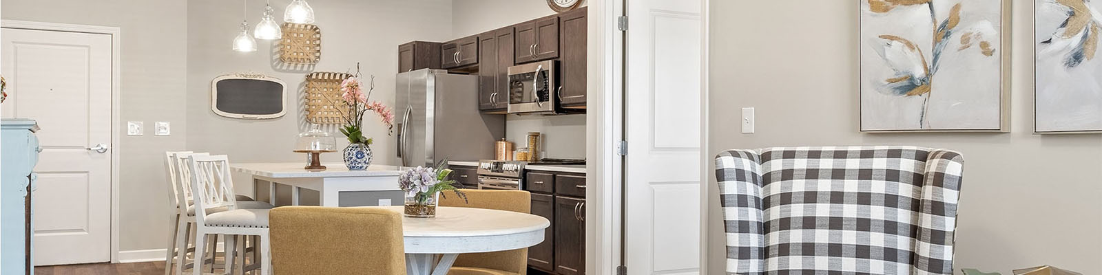 View of the inside of a furnished senior living kitchen and living room at Quincy Place Senior Living