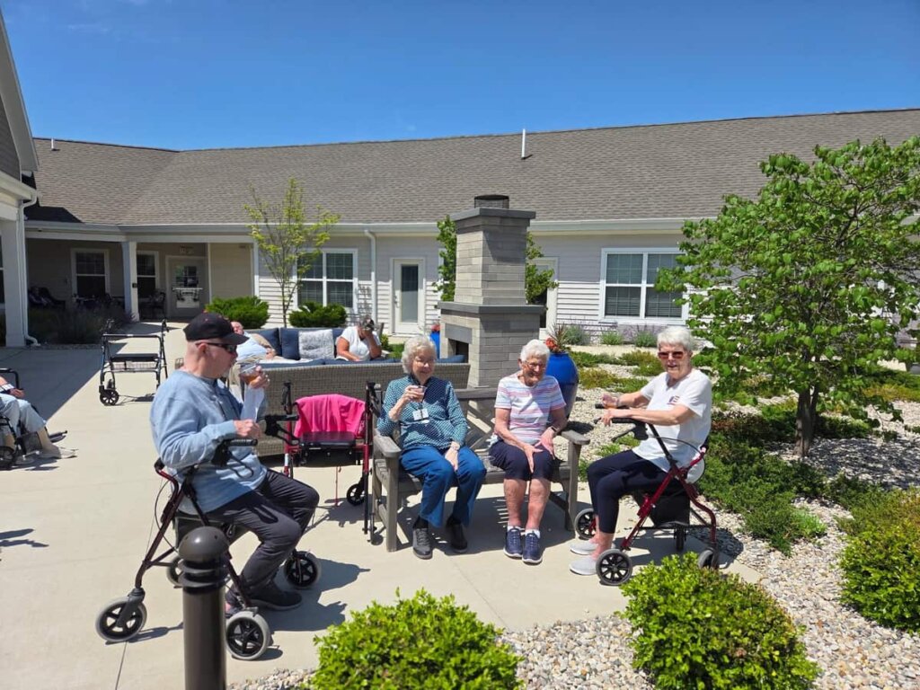 Residents enjoying drinks together on a sunny outdoor patio at Quincy Place Senior Living